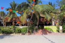 partially hidden behind palm trees is this tiki style restaurant and bar located on half moon bay between akumal beach and Yal ku lagoon