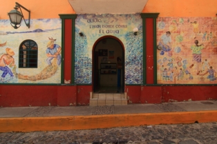 a mural on the front wall of the city hall across from the plaza